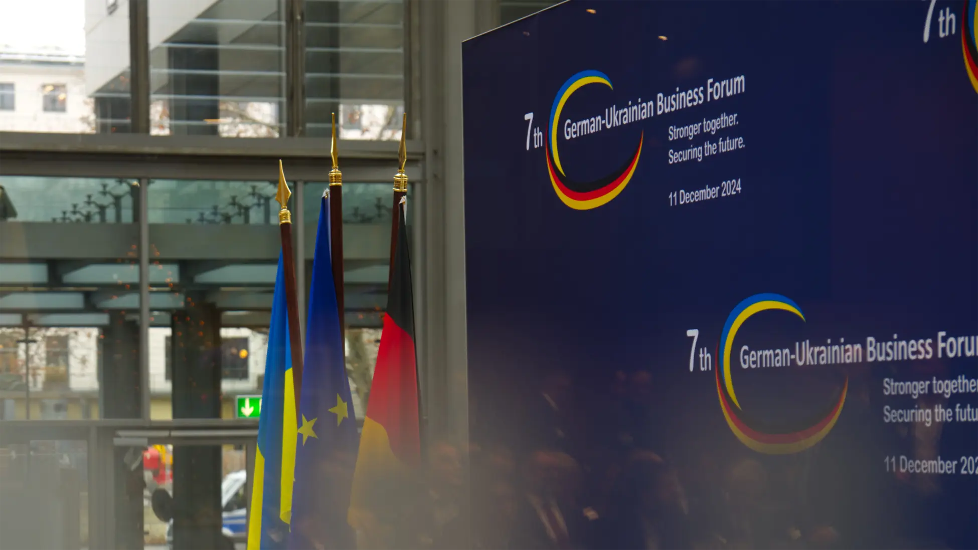 header-sehr-gross (1950x1097 px) 7. Deutsch-Ukrainisches-Wirtschaftsforum in Berlin am 11. Dezember 2024 - abgebildet sind drei Falggen (Deutschland EU, Ukraine) vor einer Stellwand