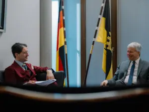 Parlamentarischer Geschäftsführer des CDU/CSU-Fraktion im Bundestag Steffen Bilger (CDU) im Gespräch mit Patrick Pehl im Jakob-Kaiser-Haus. Im Hintergrund eine Bundesflagge und eine Fahne des Landes Baden-Württemberg