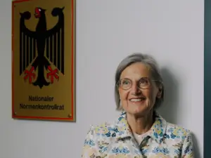 Dorothea Störr-Ritter neben dem Schild des Nationalen Normenkontrollrats in Berlin